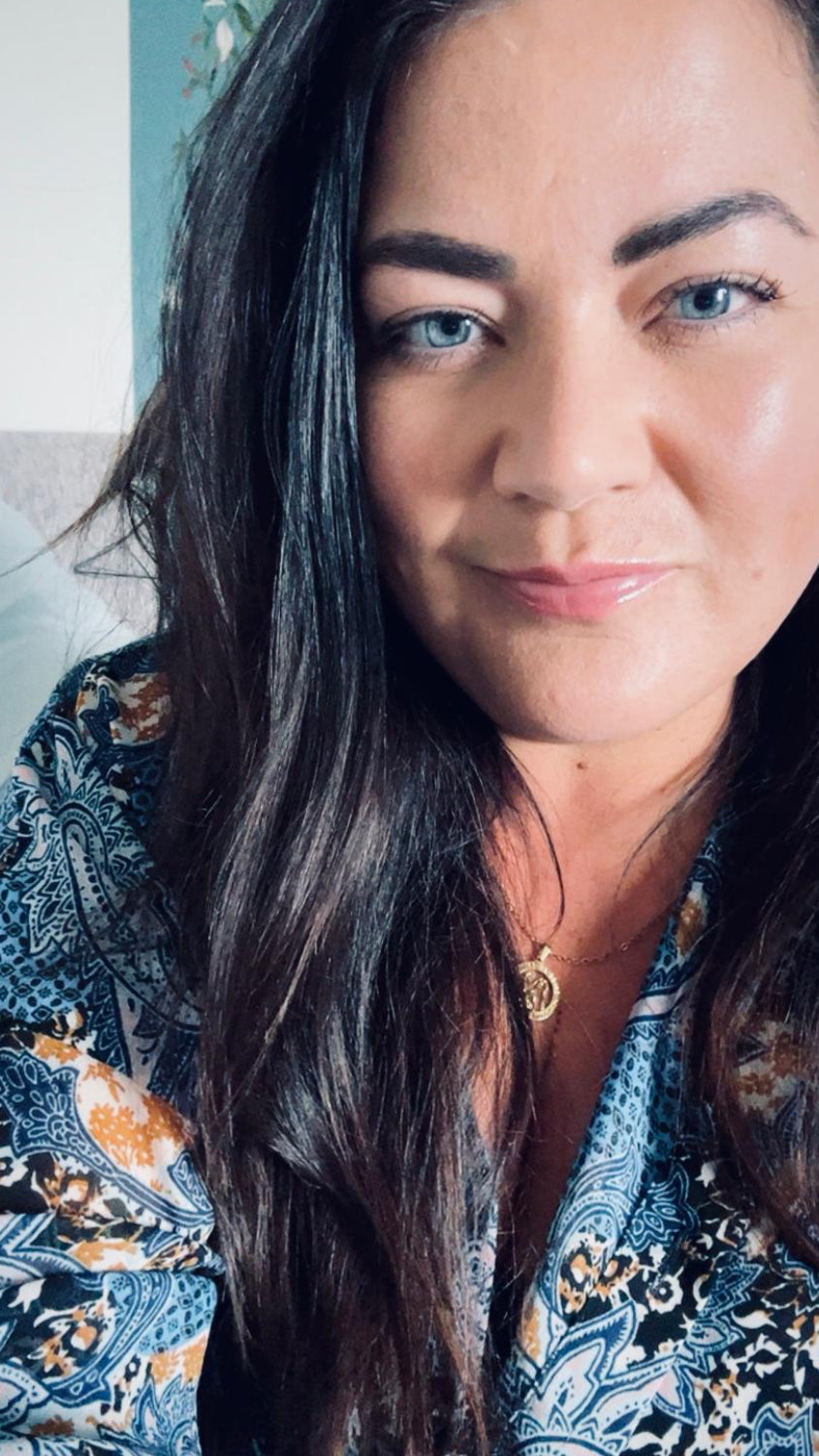 Woman with long dark hair wearing a patterned top against a neutral background